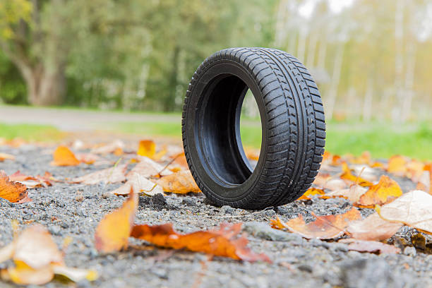 istock Black tire on the ground with fallen leaves in autumn. 611759416