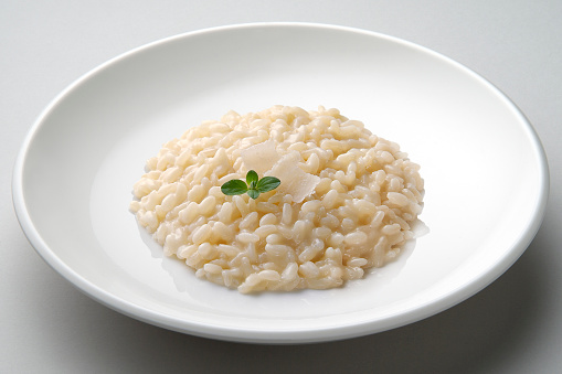 Dish of risotto with cheese isolated on grey plane
