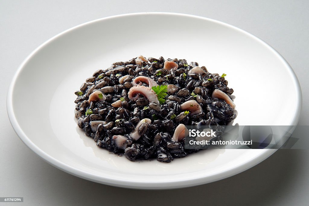 Dish of risotto with squid ink Dish of risotto with squid ink isolated on grey plane Black Color Stock Photo