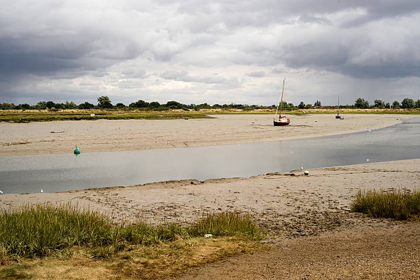 Moored boats and yachts at low tide on Maldon Estuary in Essex England during an overcast summer sky