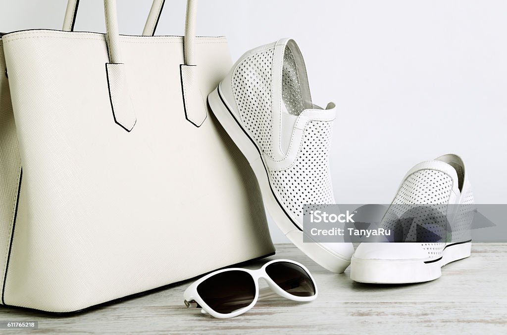 Borsa da donna bianca, scarpe e occhiali da sole su sfondo chiaro - Foto stock royalty-free di Calzature