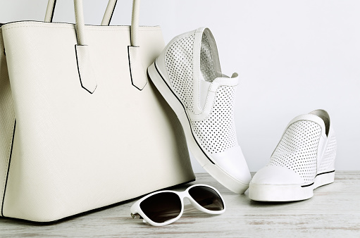 White girls handbag, shoes and sun glasses on a light background horizontal
