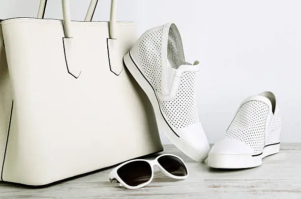 Photo of White ladies handbag, shoes and sun glasses on  light background