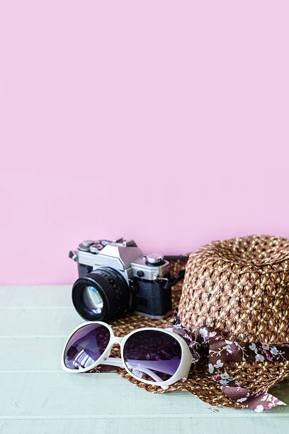istock Hat, sunglasses and camera with pink background and copyspace 611766438