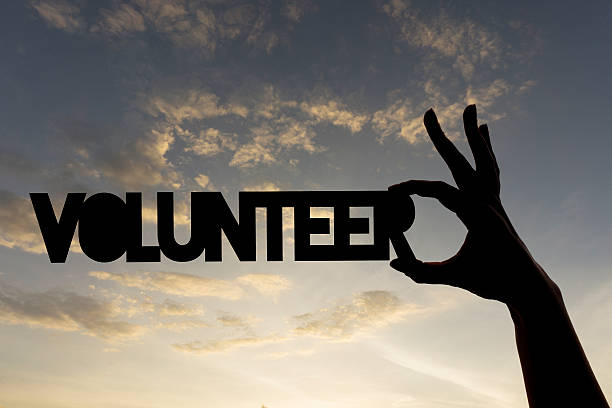istock Volunteer word being held against sky 611768574