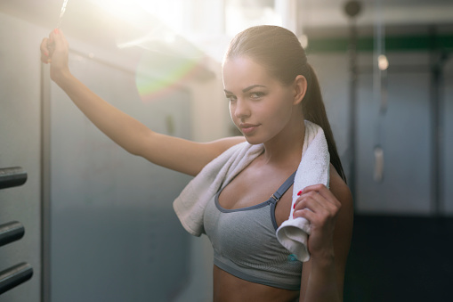 Beautiful girl with a towel around her neck, ringing the bell and having fun after hard workout