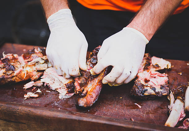 istock Hands cleaning Grilled spare beef or pork ribs from smoker. 611772266