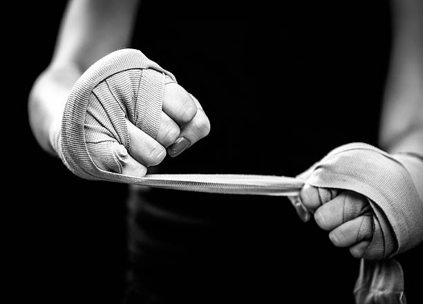 black african boxer purposefully wrapps his fists with protective tape before putting on his boxing glove