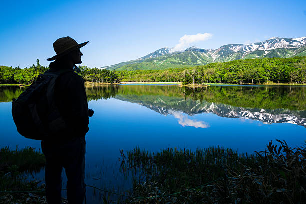 Man looking at Mountain reflection in Lake Yonko, Hokkaido, Japan