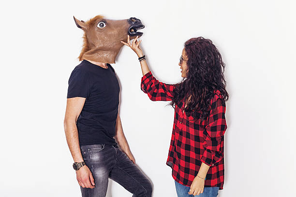 ritratto di bella ragazza che accarezza il suo ragazzo testa di cavallo - horse men animal head bizarre foto e immagini stock