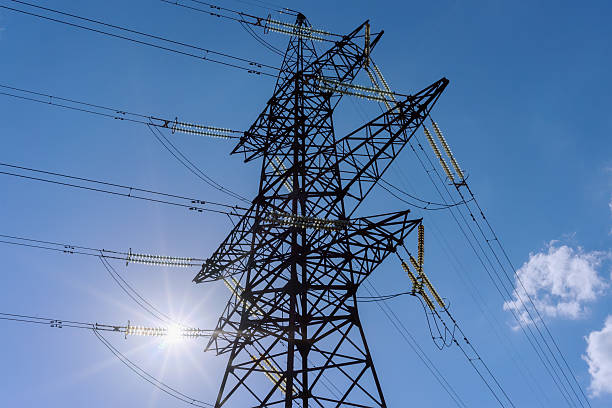 istock Electricity pylons and lines, sun-through insulators against 611774042