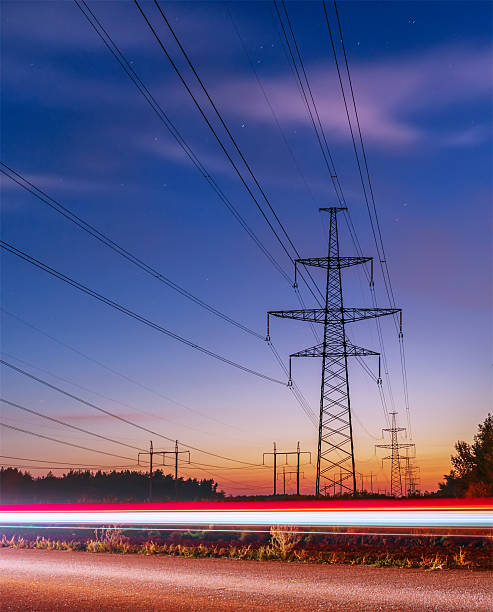 istock Pylons and electricity powerlines at night with traffic 611774680