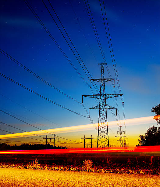 istock Pylons and electricity powerlines at night with traffic 611774732