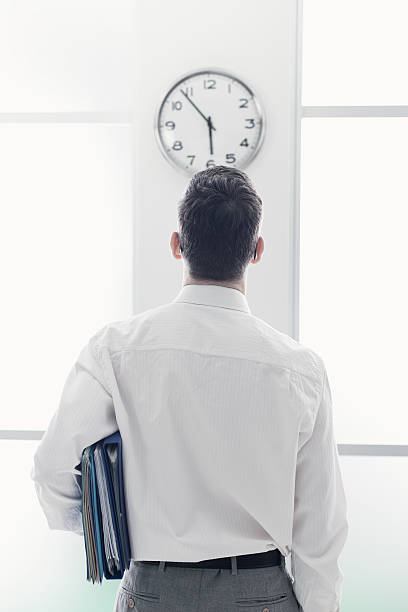ビジネスマン見つめるの時計 - 定時で仕事が終わる人 ストックフォトと画像