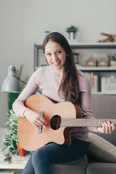 istock Girl playing guitar at home 611775550