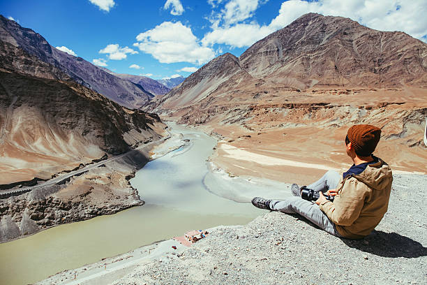 istock Young happy man sitting on the cliff on the trip 611777604