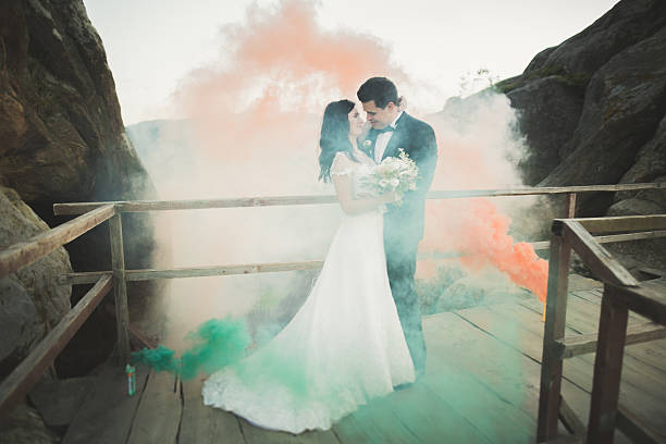 istock Wedding couple posing near rocks with colored smoke behind them 611781006