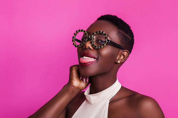 chica africana divertida con la lengua pegada con unas gafas extrañas - bizarre women portrait pierced fotografías e imágenes de stock