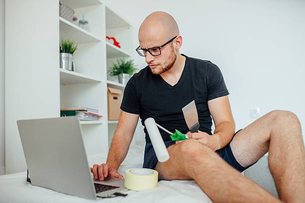 Young man is holding painting tools and using laptop pc. stock photo