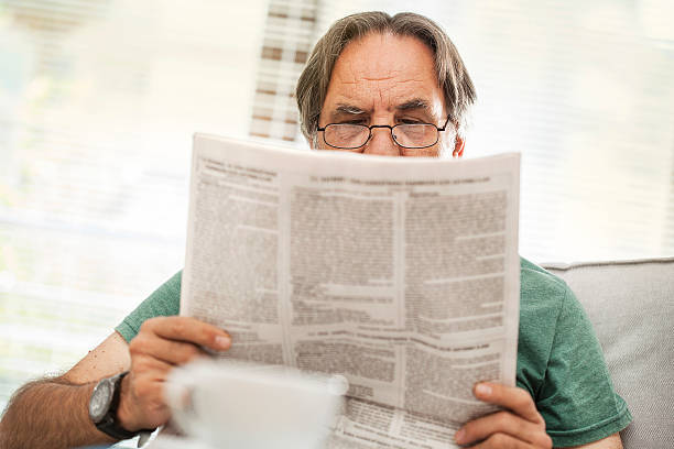 istock Senior man reading newspaper in home 611856372