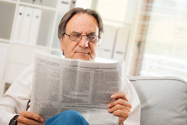 istock Senior man reading newspaper in home 611856636