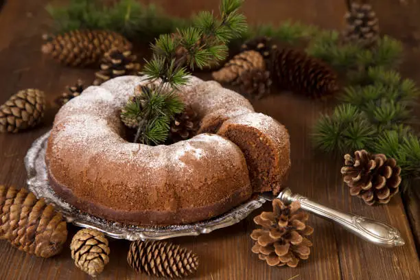 Bundt cake with pine branches on wooden table