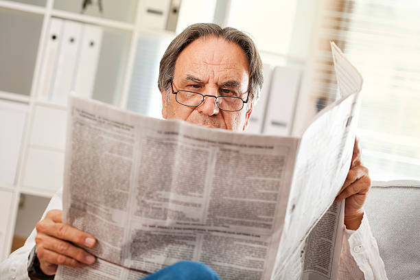 istock Senior man reading newspaper in home 611856916