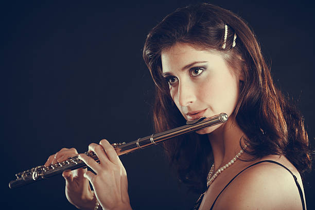 istock Woman playing transverse flute on black. 611859734