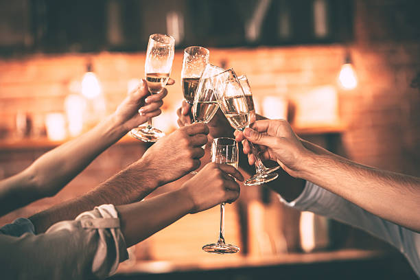Cheers! Group of people cheering with champagne flutes with home interior in the background champagne flute stock pictures, royalty-free photos & images