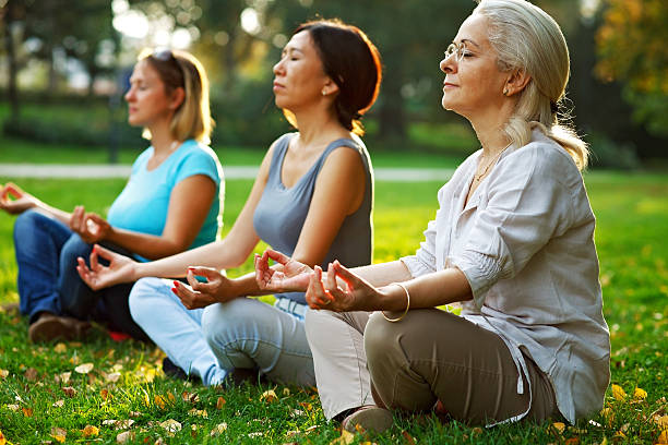 yoga in der natur  - yoga exercising outdoors group of people stock-fotos und bilder