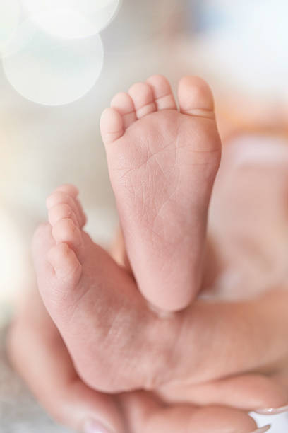 unrecognizable baby boy feet in his mother hands, vertical shot.new born and begginings concept.