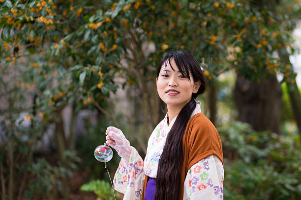 日本の風鈴を持って公園を歩く若い浴衣女