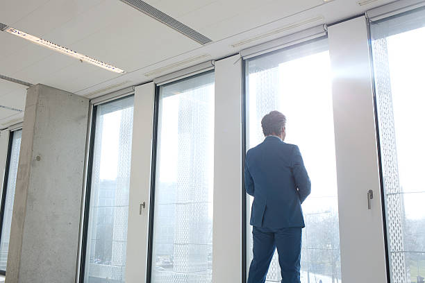 istock Rear view of mature businessman looking through office window 611861732