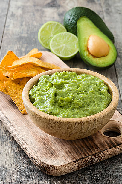 Nachos, guacamole and ingredients Nachos, guacamole and ingredients on wooden background guacamole stock pictures, royalty-free photos & images