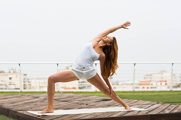 Beautiful woman doing yoga outdoors on a rooftop terrace stock photo