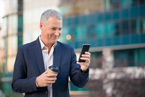 istock Happy businessman having coffee break using his smartphone 611863150