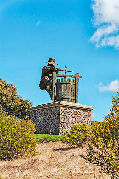 Napa, California, USA - October 2, 2016: This statue welcoming visitors to the world famous Napa Valley rest atop a hill that welcomes you to this grape and wine region of Northern California along Highway 121 at this wonderful viewfull vista point, on a day like this with beautiful cloudy sky the statue representing a grape crusher in the old world fashion and on this beautiful cloudy sky in October it was beautiful.