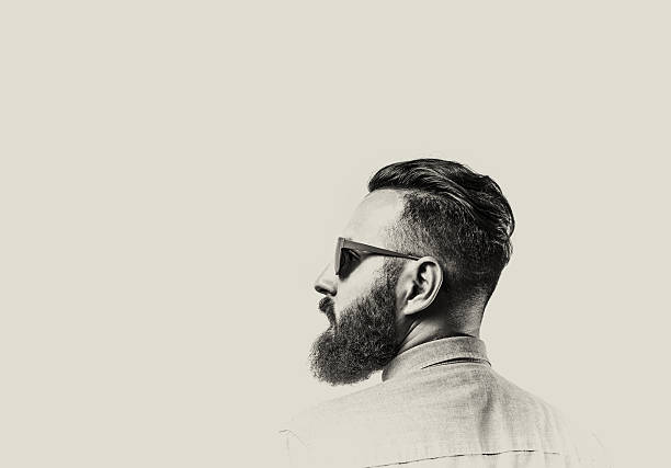 Bearded man with glasses Black and white portrait of a Bearded Man in a denim shirt and glasses  on toned background. There is a spase for your text. black and white men facial hair beard stock pictures, royalty-free photos & images