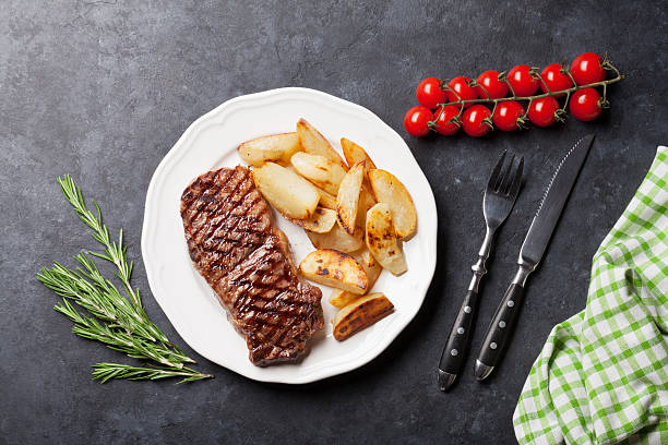 구운 스트리핀 스테이크와 구운 감자 - rib eye steak steak beef prepared potato 뉴스 사진 이미지