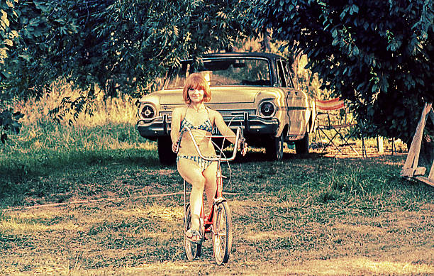 woman riding on bike in a summer day Vintage image form the seventies of a woman riding on bike in a summer day at the countryside. 1970s woman stock pictures, royalty-free photos & images