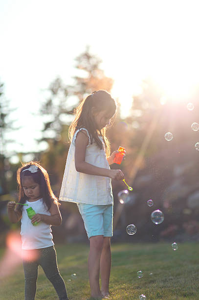 istock Two young ethnic girls blowing bubbles in the backyard 611886432