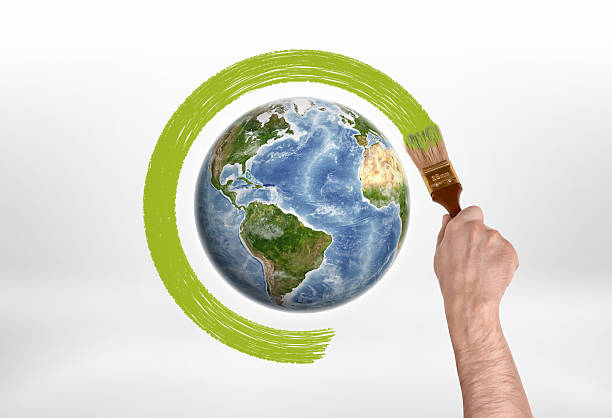 istock Man's hand encircles globe green paint with brush 611886718