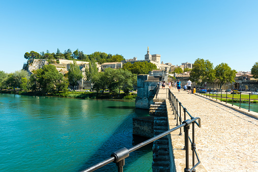 Avignon, France - August 13, 2016: walking along Pont Saint-Benezet in Avignon. View to popes palace in background.