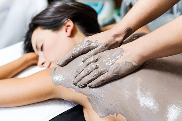 hermosa mujer joven que tiene máscara de cuerpo de arcilla aplicar por esteticista. - mud wellbeing spa treatment beautician fotografías e imágenes de stock