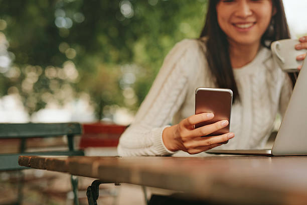 giovane donna in una caffetteria utilizzando il telefono cellulare  - convenience foto e immagini stock