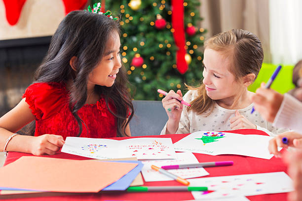 istock Two diverse young girls creating Christmas greeting cards 611890420