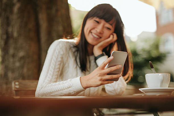 istock Smiling woman using smartphone in cafe 611890484