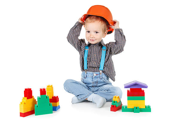 bambino in un elmetto costruzione rossa su sfondo bianco - child building activity construction engineer foto e immagini stock