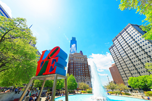 Philadelphia, United States - May 4, 2015: Love sculpture in Love Park in Philadelphia, Pennsylvania, USA. Tourists in the park. Skyline with skyscrapers on the background