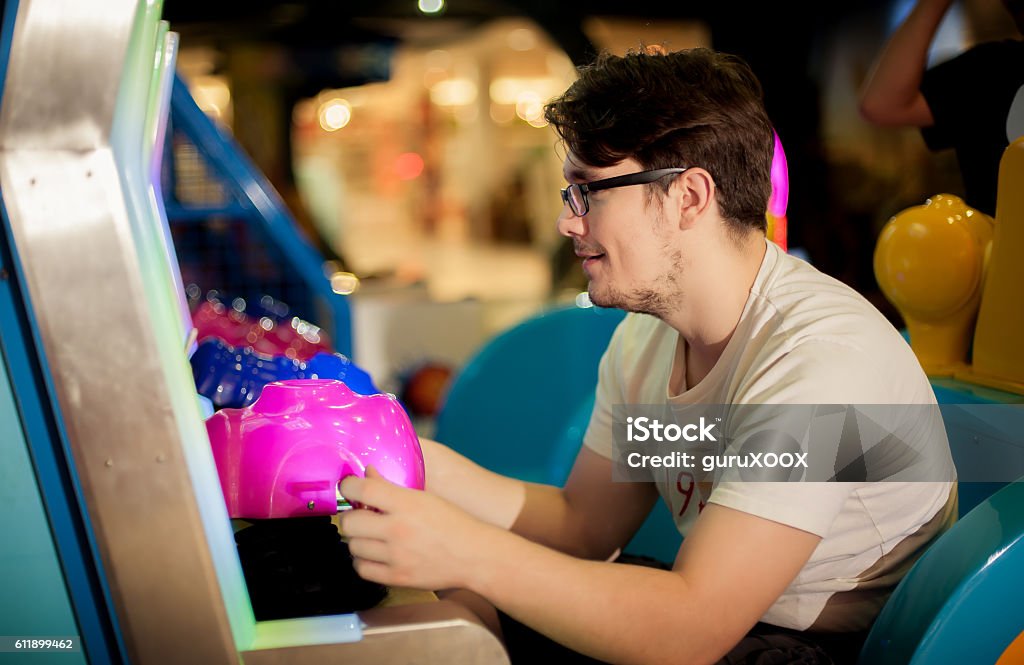 Young man have fun on the game room Happy young man playing games on the game room Amusement Arcade Stock Photo